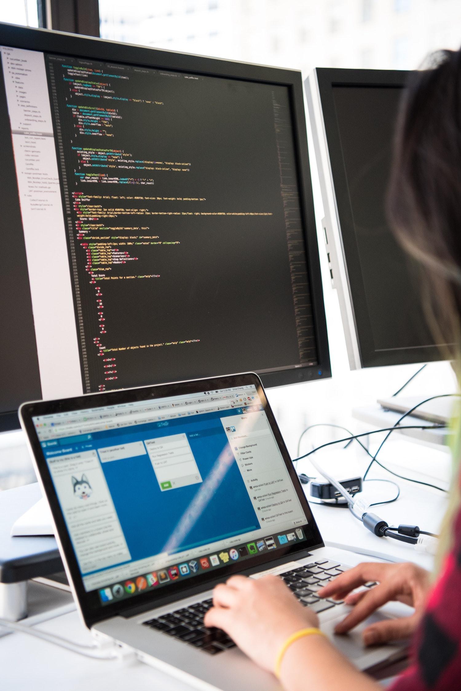 Girl coding on laptop and desktop screen. Custom Software Australia.